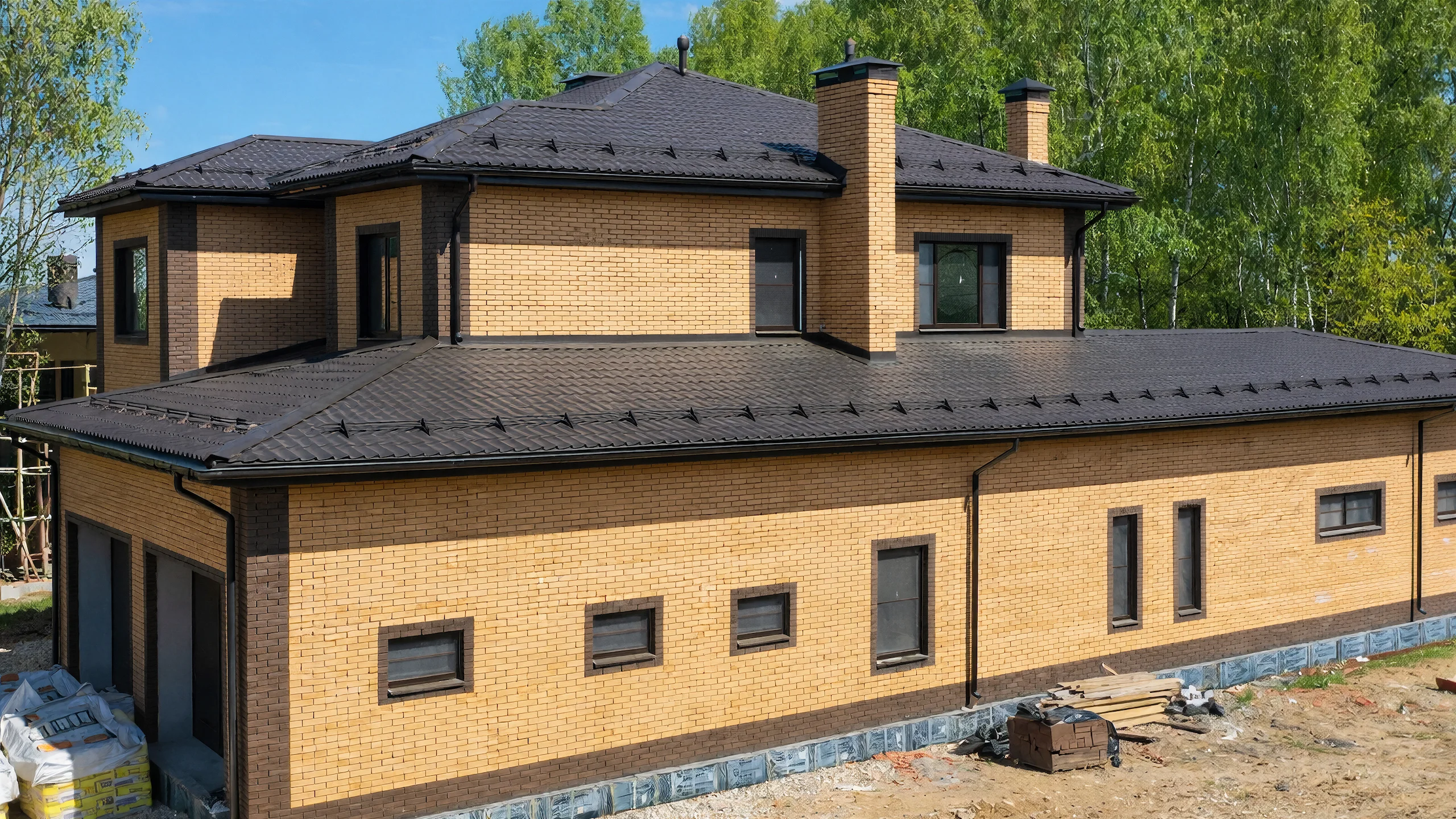 Боковой фасад построенного каменного дома 382 м² с большими окнами