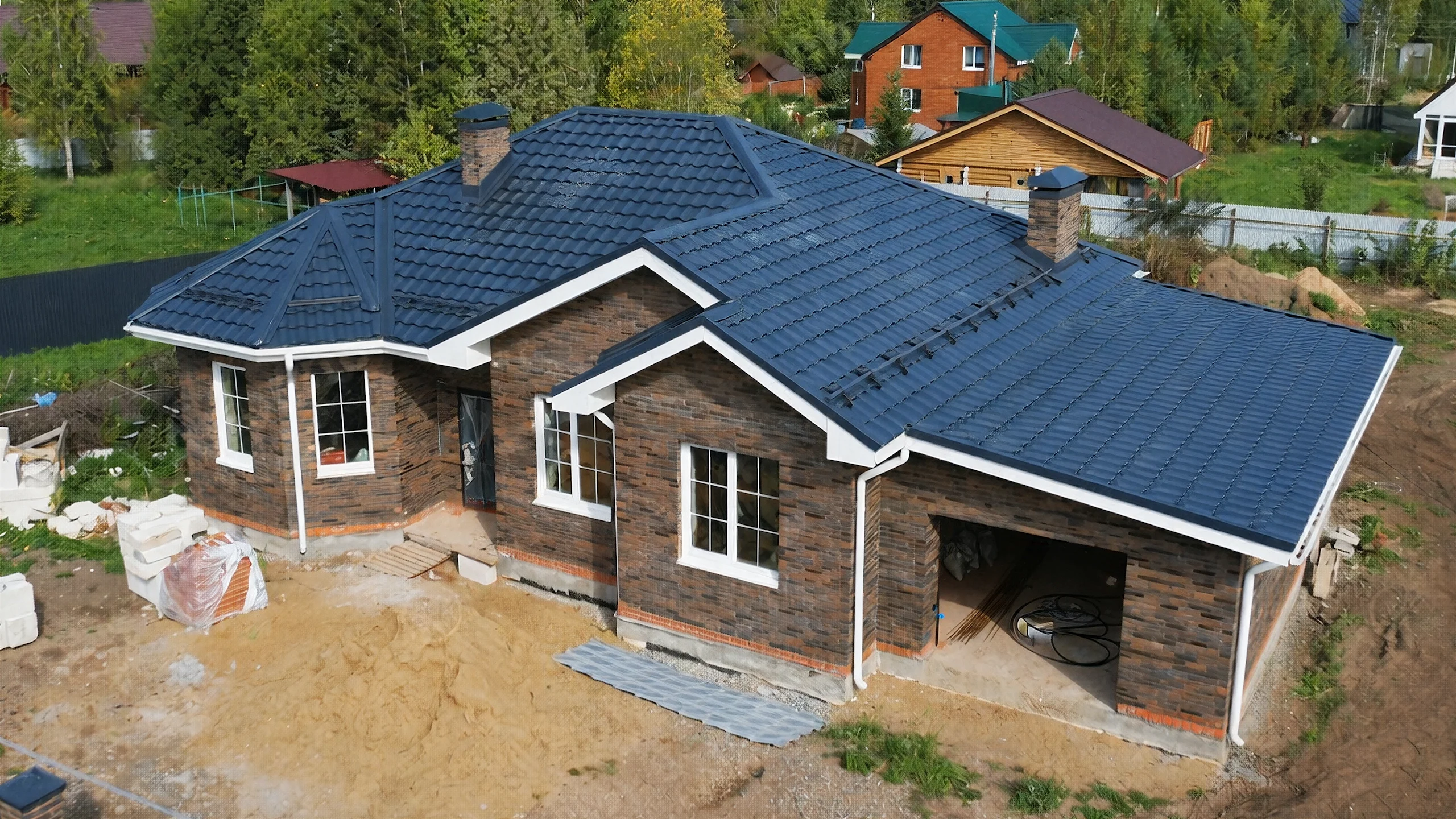 Боковой фасад построенного каменного дома 168 м² с большими окнами