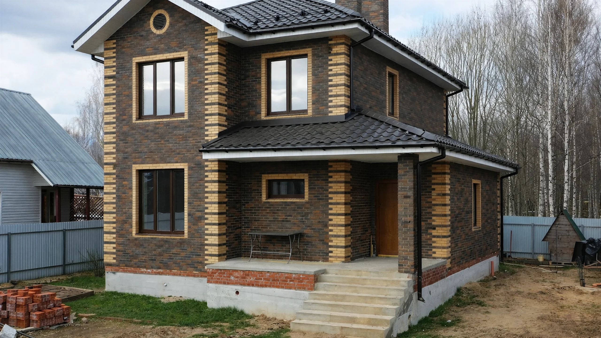 Боковой фасад построенного каменного дома 132 м² с большими окнами