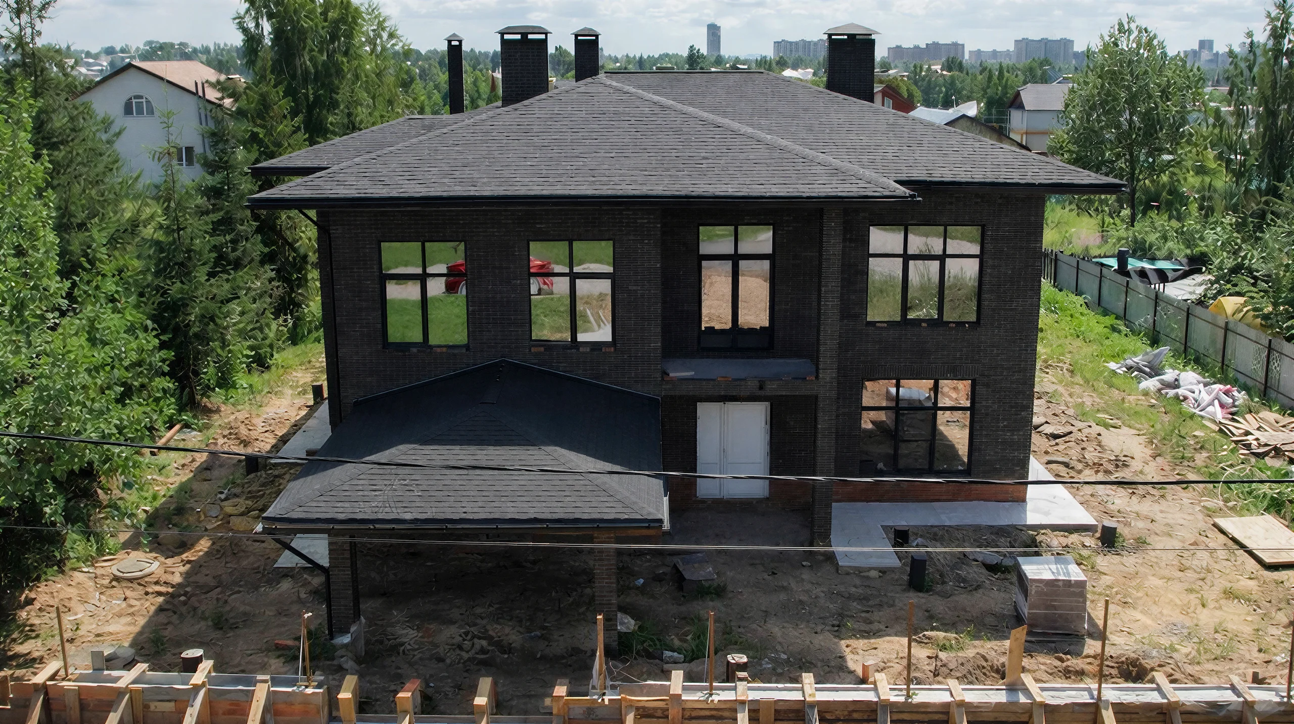 Дом Скуратов 365 м² с темным кирпичным фасадом, вальмовой кровлей и крытым навесом